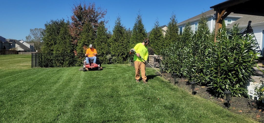 Two gardeners mowing and edging a tidy suburban lawn