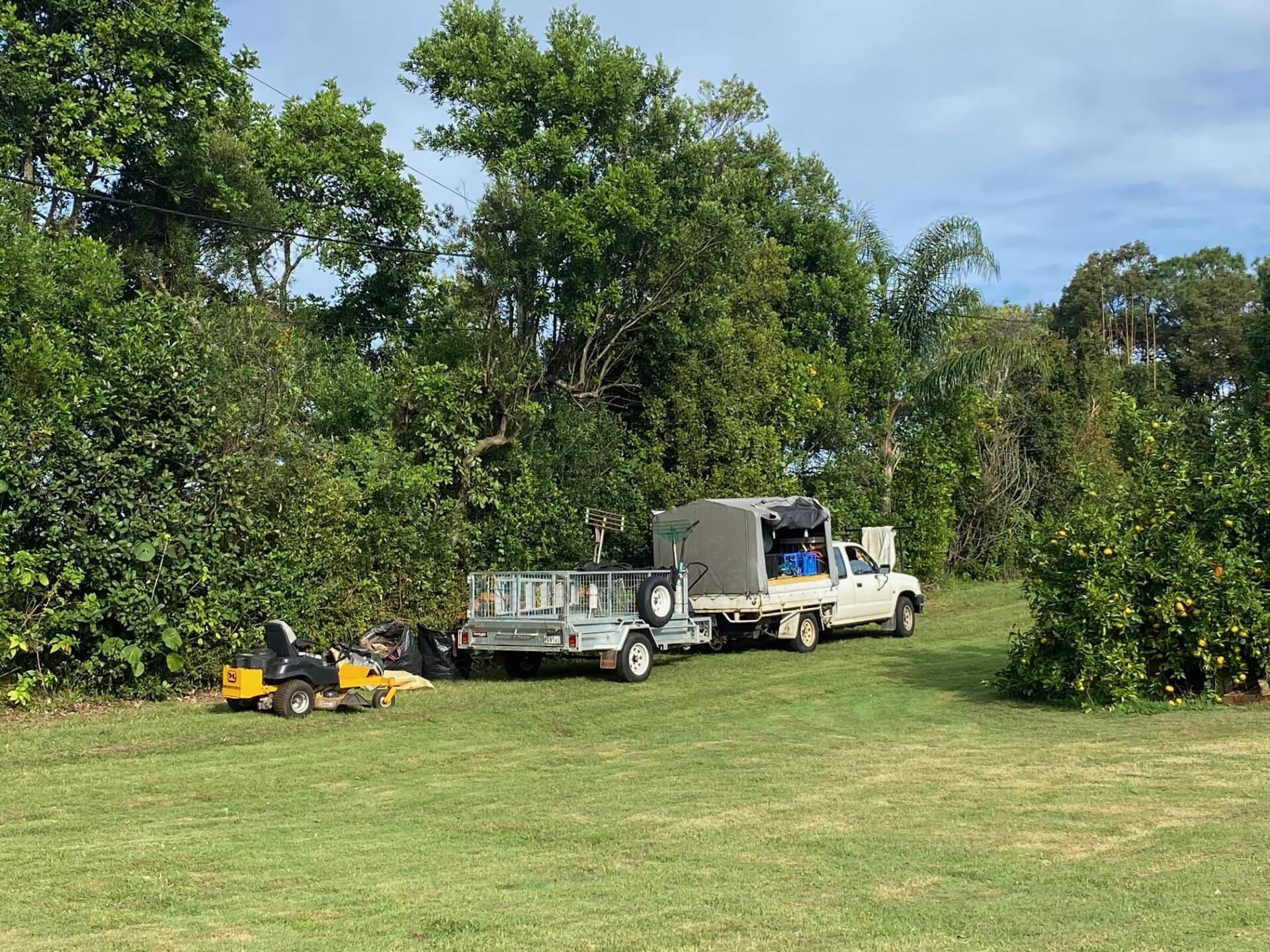 Tucki Gardens ride-on mower, trailer and ute on a freshly mown acreage block in the Northern Rivers